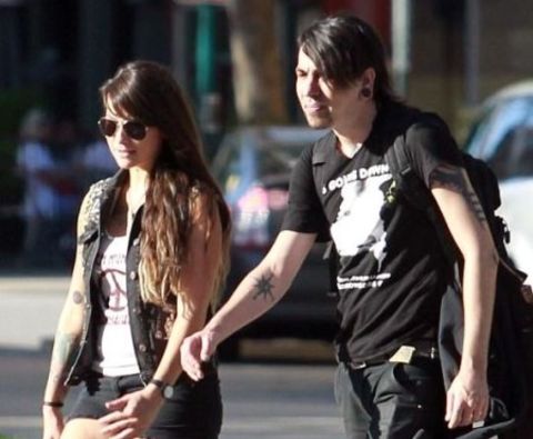 Alex Aniston in a black t-shirt poses with girlfriend Kiri Peita.