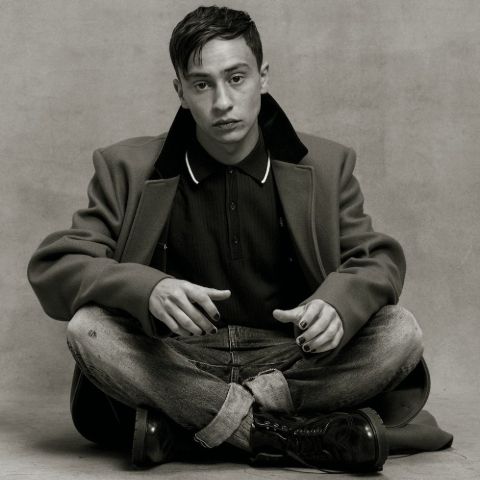 Keir Gilchrist in brown jacket poses for a photoshoot.