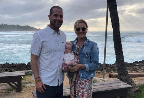 Kevin Simshauser in a white shirt poses with his new daughter and wife Taylor Cole.