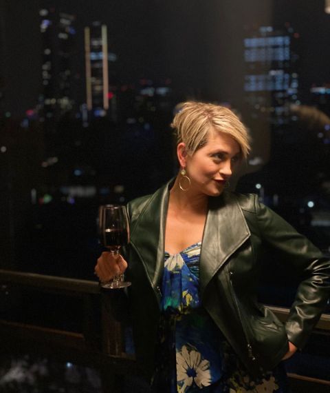 Jamie Yuccas poses for a picture with a wine glass on her hand.