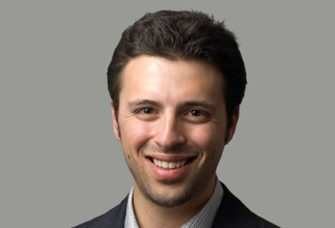 Ezra Klein in a black suit poses for a picture.