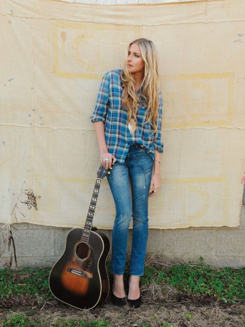 Holly Williams in her jeans pant and blue shirt poses a picture with her guitar.