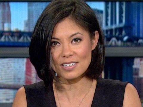 Alex Wagner in a black dress poses for a picture.
