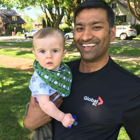 Shanel Pratap in a black t-shirt poses a picture with his baby.