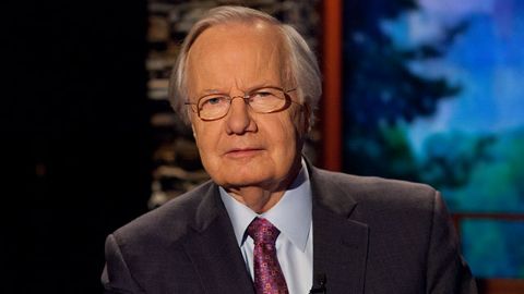 Bill Moyers in a black suit poses for a picture.