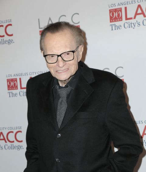 Larry King in a black suit poses for a picture.