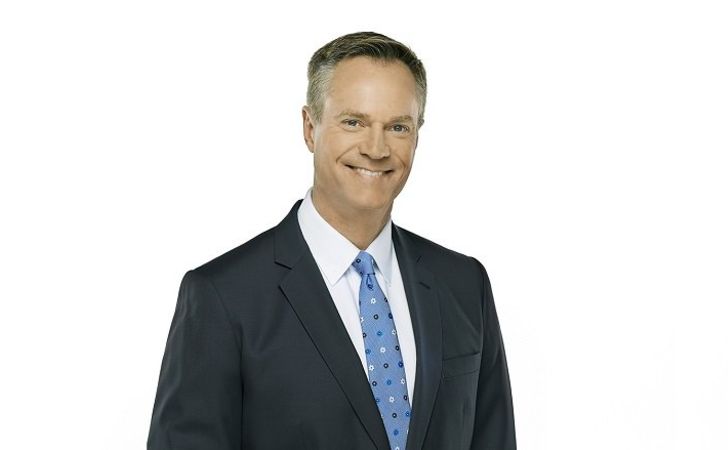 Chris Gailus in a black suit poses for a picture.
