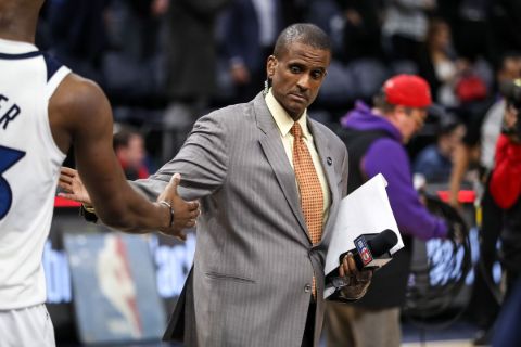David Aldridge in a grey suit shaking hand with a NBA player.