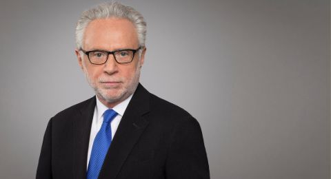 Wolf Blitzer in a black suit poses for a picture.
